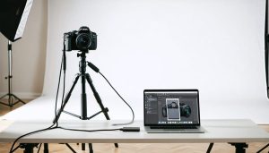 A Canon DSLR camera connected to a laptop displaying the EOS Utility interface, depicting a professional tethered shooting setup in a photography studio.