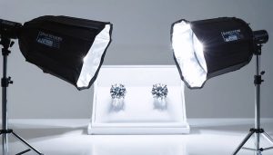 Professional studio setup for jewelry photography showcasing meticulous lighting arrangement with softboxes, LED strip, and diffuser highlighting diamond earrings.