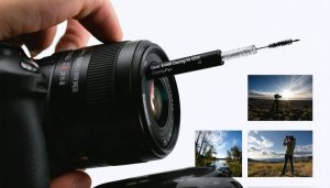 A dual-ended lens cleaning pen highlighting the retractable brush and carbon tip, used to clean a camera lens against a background of photography settings.