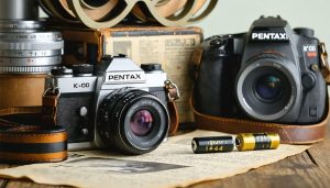 Illustration of a Pentax K1000 camera with SR44 and LR44 batteries, surrounded by vintage photography elements, representing reliability and longevity.