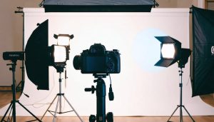 Conceptual image of a professional video lighting setup featuring three-point lighting with labeled key, fill, and back lights, demonstrating a mix of traditional and budget-friendly lighting solutions.