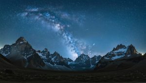 "The Milky Way galaxy forming a dramatic arch over rugged mountain peaks under a pristine dark sky."