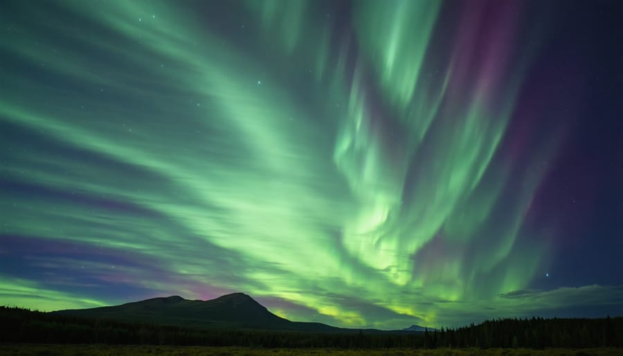 Green and purple aurora borealis over snow-covered mountains and forest at night