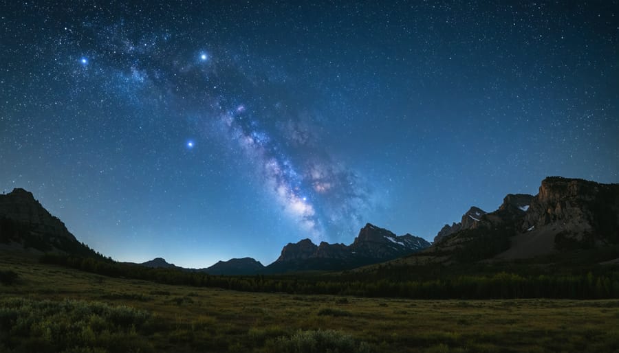 Milky Way galaxy stretching across night sky above silhouetted mountain landscape