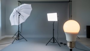 Photo studio lighting setup with an LED light panel on a stand, a diffuser umbrella, and a smart LED bulb glowing against a neutral backdrop.